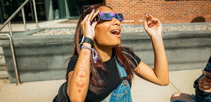 A student wearing glasses gazes at the eclipse.